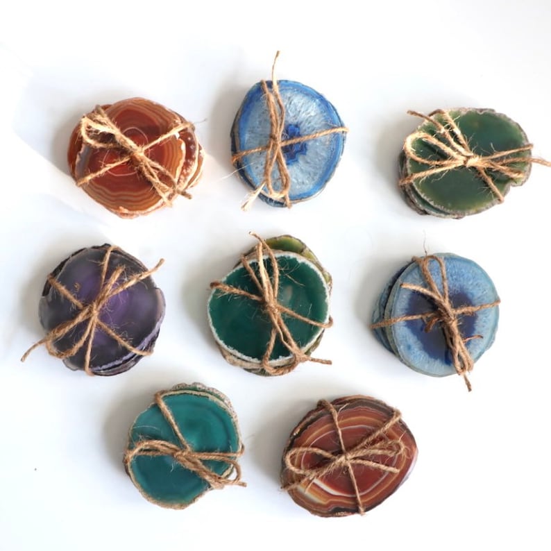 Peut inclure: Ensemble de neuf sous-verres en agate de diff&eacute;rentes couleurs, dont le violet, le vert, le bleu et le brun. Chaque sous-verre est fait d'une tranche d'agate naturelle et est li&eacute; avec de la ficelle.