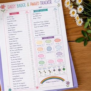 Könnte beinhalten: Ein weißes Daisy Badge & Award Tracker-Blatt aus Papier mit bunten Überschriften, Listen von Abzeichentiteln, einem Blütenblatt-Tracker-Bereich mit pastellfarbenen Ovalen und einer Regenbogen-Grafik mit der Aufschrift Bridging to Brownies Award.