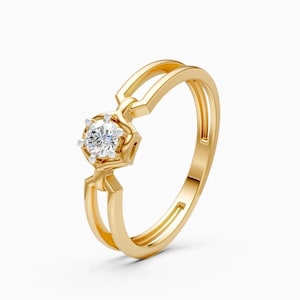 Op de afbeelding: Een gouden ring met een enkele ronde, briljant geslepen witte edelsteen in een zeshoekige zetting. De ringband heeft een gespleten ontwerp dat samenkomt bij de zetting, wat zorgt voor een open, geometrische uitstraling met een gepolijste afwerking.