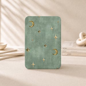 May include: A rectangular tablet case featuring a sage green textured background with a repeating pattern of gold-colored crescent moons and four-pointed stars scattered across the surface in a celestial-inspired design.