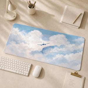 Peut inclure: Un tapis de bureau rectangulaire présentant une illustration imprimée d'un avion de ligne volant à travers une vaste étendue de nuages blancs et bleu clair. Le motif couvre toute la surface du tapis, montrant un ciel clair avec des nuages duveteux.