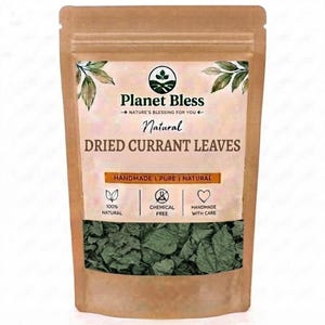 Op de afbeelding: Een bruine papieren zak met gedroogde aalbessenbladeren. Het etiket bevat de tekst Planet Bless, Natural DRIED CURRANT LEAVES en iconen voor 100% natuurlijk, chemicaliënvrij en handgemaakt. Het onderste gedeelte toont de groene bladeren.