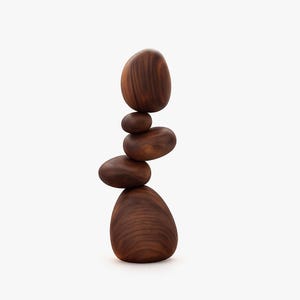 May include: A vertical stack of five smooth, polished dark brown wooden stones of varying sizes. The stones are balanced on top of one another, creating a tall, rounded sculpture with visible wood grain patterns throughout the dark brown surface.