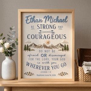 May include: A framed embroidery art piece on cream fabric featuring the text Ethan Michael BE STRONG AND COURAGEOUS DO NOT BE afraid OR discouraged FOR THE LORD, YOUR GOD is with you WHEREVER YOU GO JOSHUA 1:9 Baptized June 14, 2026.