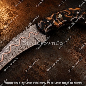 Puede incluir: Un cuchillo karambit curvo con una hoja de acero de Damasco con una incrustaci&oacute;n ondulada de cobre. El mango est&aacute; hecho de un material oscuro y veteado con pasadores met&aacute;licos y un anillo en forma de estrella en el pomo.