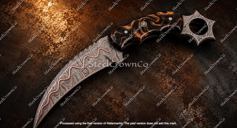 Puede incluir: Un cuchillo karambit curvo con una hoja de acero de Damasco con una incrustaci&oacute;n ondulada de cobre. El mango est&aacute; hecho de un material oscuro y veteado con pasadores met&aacute;licos y un anillo en forma de estrella en el pomo.