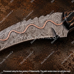 Puede incluir: Un cuchillo karambit curvo con una hoja de acero de Damasco que presenta una incrustaci&oacute;n de cobre ondulada a lo largo del lomo. El mango est&aacute; hecho de madera oscura pulida con patrones marrones en espiral y un detalle de incrustaci&oacute;n circular.