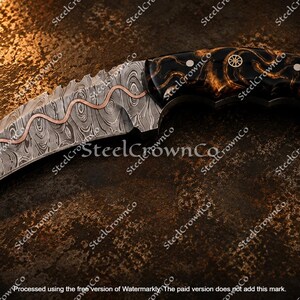 Puede incluir: Un cuchillo karambit curvo con hoja de acero de Damasco y una incrustaci&oacute;n de cobre ondulada. El mango est&aacute; hecho de un material oscuro y veteado, con un anillo circular para el dedo en el pomo, asegurado por dos pasadores de tono plateado.