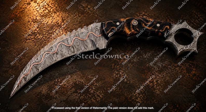 Puede incluir: Un cuchillo karambit curvo con hoja de acero de Damasco y una incrustaci&oacute;n de cobre ondulada. El mango est&aacute; hecho de un material oscuro y veteado, con un anillo circular para el dedo en el pomo, asegurado por dos pasadores de tono plateado.