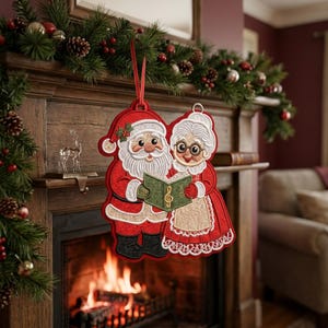 May include: A hanging Christmas ornament featuring an embroidered design of Santa Claus and Mrs. Claus standing side by side. They are holding a green songbook with a gold treble clef symbol. The ornament has a red ribbon loop for hanging.