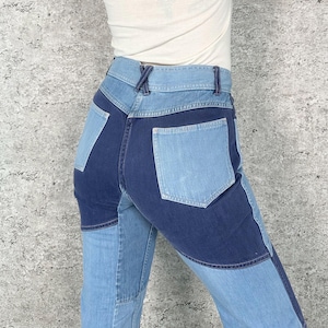 May include: Light and dark blue denim jeans with a patchwork design. The jeans feature a high waist and a straight leg cut. The back pockets are a lighter shade of blue, and the overall style is vintage.