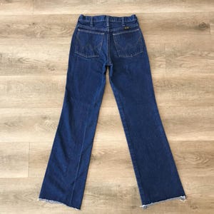 May include: A pair of dark blue denim jeans with a frayed hem. The jeans have a high waist and a wide leg.