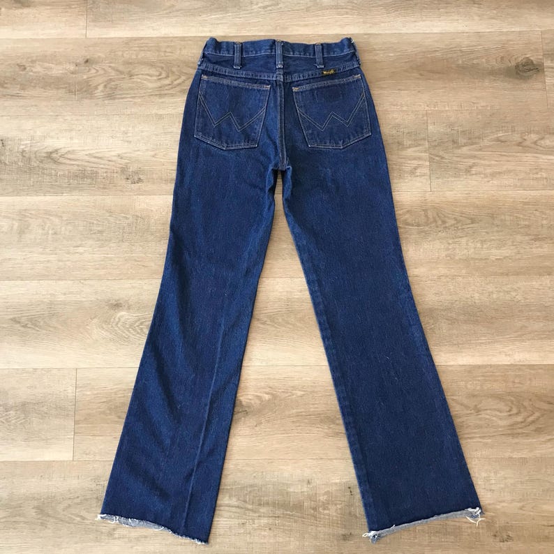 May include: A pair of dark blue denim jeans with a frayed hem. The jeans have a high waist and a wide leg.