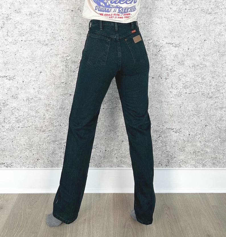 Op de afbeelding: Donkerblauwe denim jeans met een hoge taille en een rechte pijp. De jeans hebben een klassiek ontwerp met vijf zakken en een kleine bruine patch op de achterzak. Het model draagt een wit T-shirt.