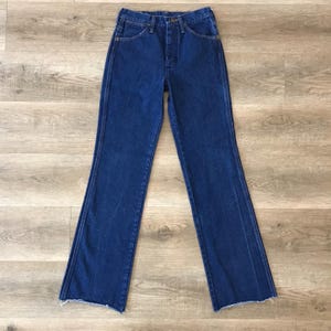 May include: A pair of blue denim jeans with a high waist and a wide leg. The jeans have a button fly and belt loops.