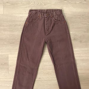 Op de afbeelding: Een paar mauvekleurige jeans. De jeans hebben een klassiek ontwerp met vijf zakken en een knoop- en ritssluiting. De jeans zijn gemaakt van stevig denim en hebben een rechte pijp.