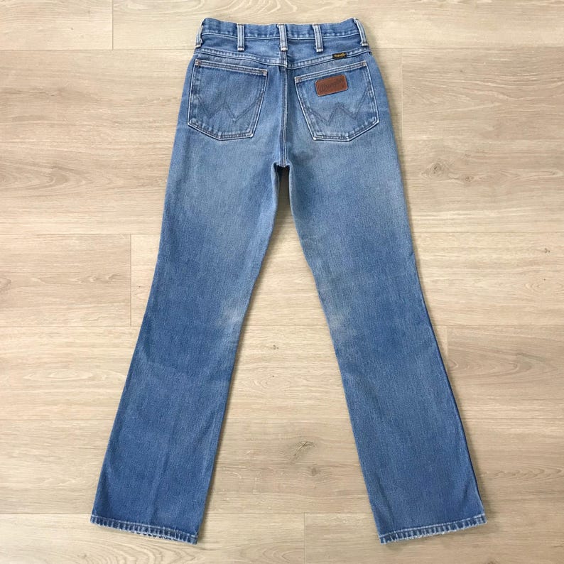 Op de afbeelding: Lichtblauwe denim jeans met een klassiek vijf-zakken ontwerp. De jeans hebben het Wrangler-logo op de achterzak en een bruine leren patch. De jeans hebben een rechte pijp.
