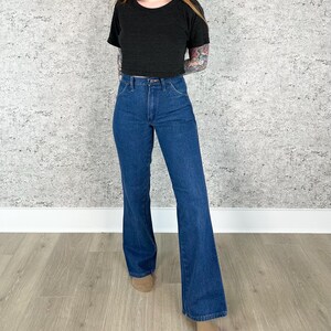 May include: A pair of blue denim flared jeans with a high waist. The jeans have a classic five-pocket style and a wide leg opening.