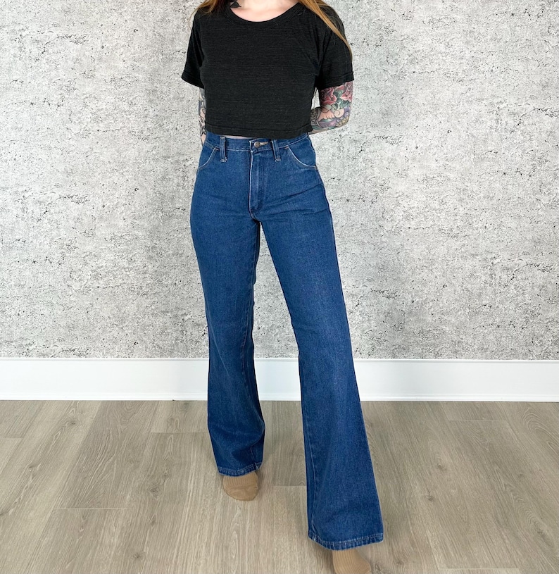 May include: A pair of blue denim flared jeans with a high waist. The jeans have a classic five-pocket style and a wide leg opening.