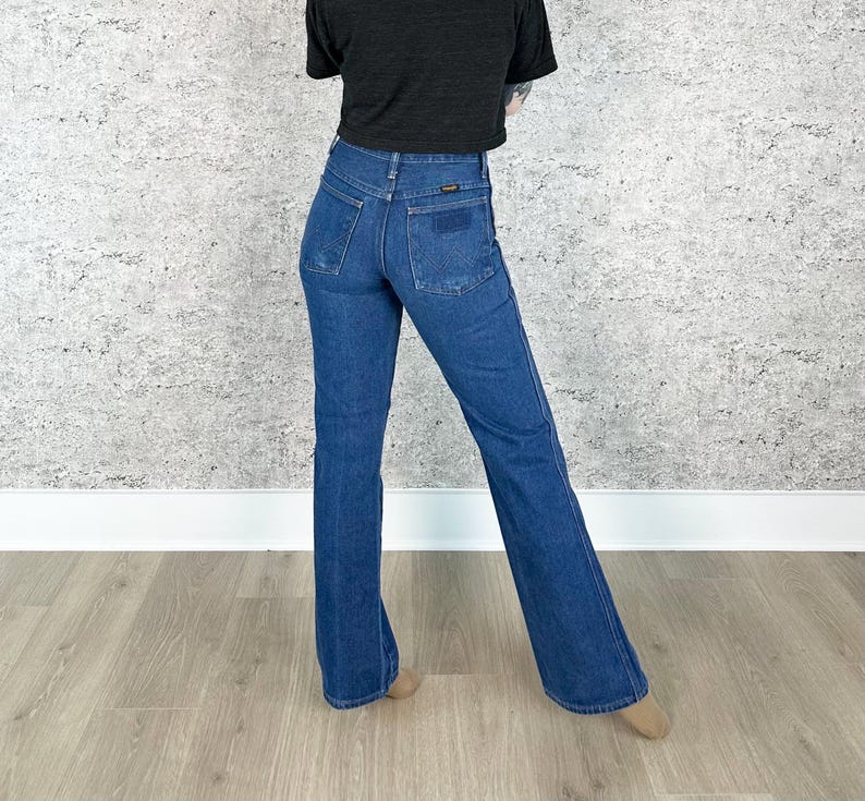 May include: A pair of blue denim flared jeans with a high waist and a small brown leather patch on the back.