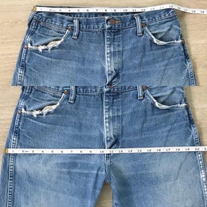 K&ouml;nnte beinhalten: Hellblaue Jeans mit klassischem F&uuml;nf-Taschen-Design. Die Jeans haben einen Knopf- und Rei&szlig;verschluss, und die Taille misst ca. 48 cm. Die Jeans haben abgenutzte Details an den Vordertaschen.