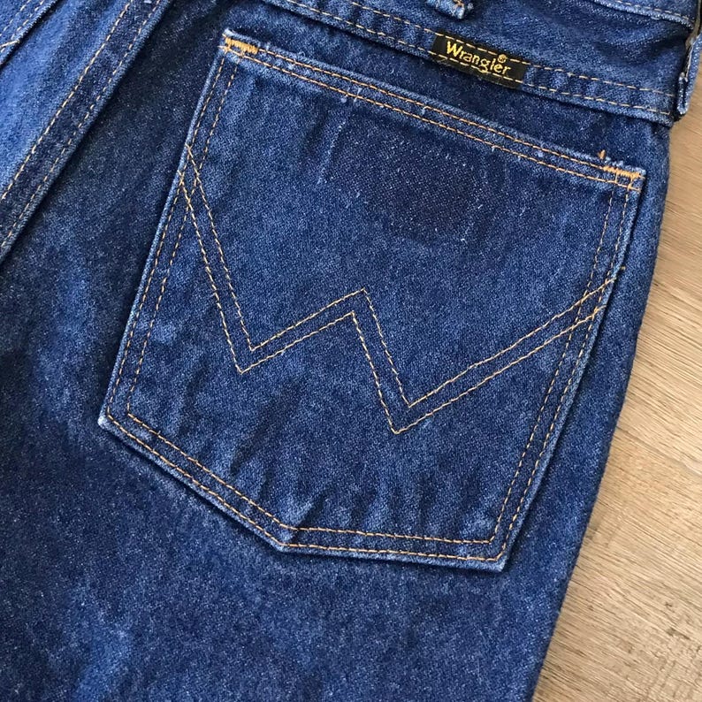 May include: A close-up of a blue denim back pocket with a stitched-in