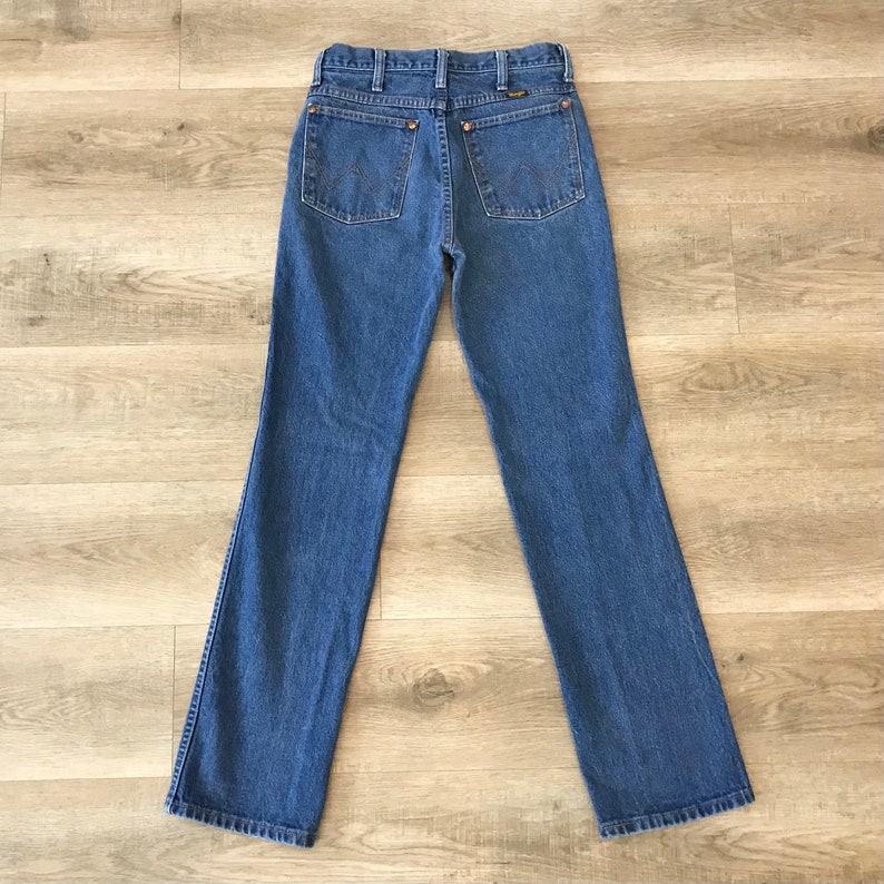 K&ouml;nnte beinhalten: Eine blaue Jeans mit geradem Bein. Die Jeans hat ein klassisches F&uuml;nf-Taschen-Design und ein braunes Leder-Patch auf der R&uuml;ckseite.