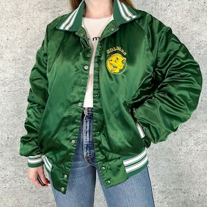 May include: Green satin jacket with white and green striped trim on the collar, cuffs, and hem. The jacket features a snap-front closure and a yellow and green logo that says "Holmes Huskies".