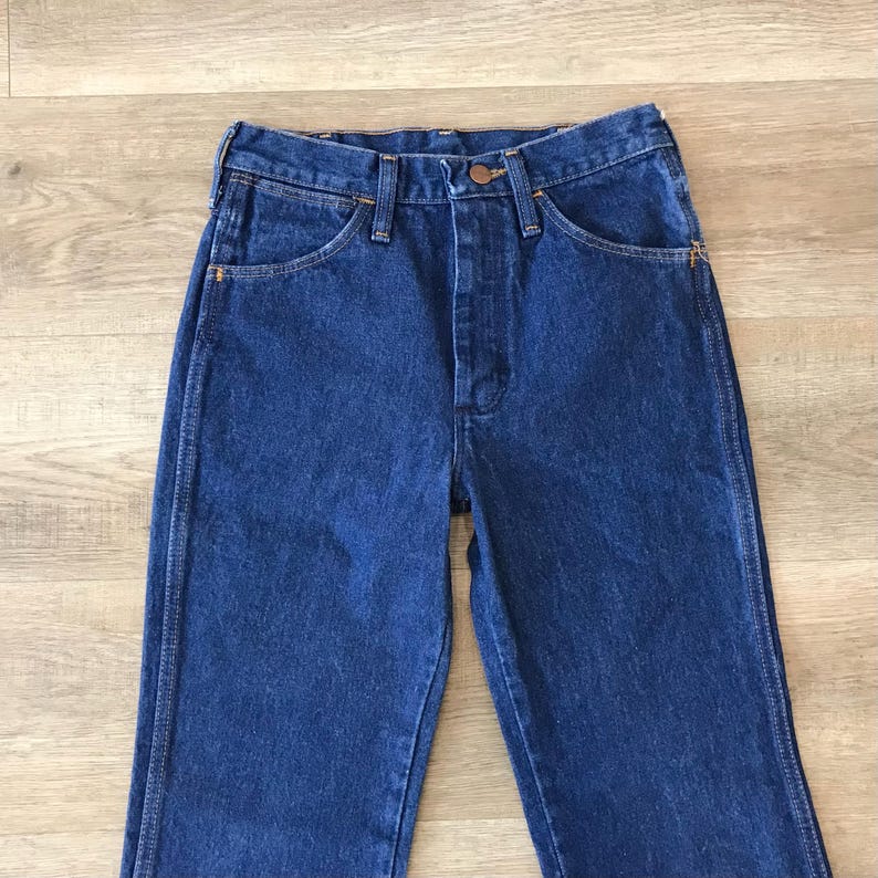 May include: A pair of dark blue denim jeans with a button fly and five pockets.