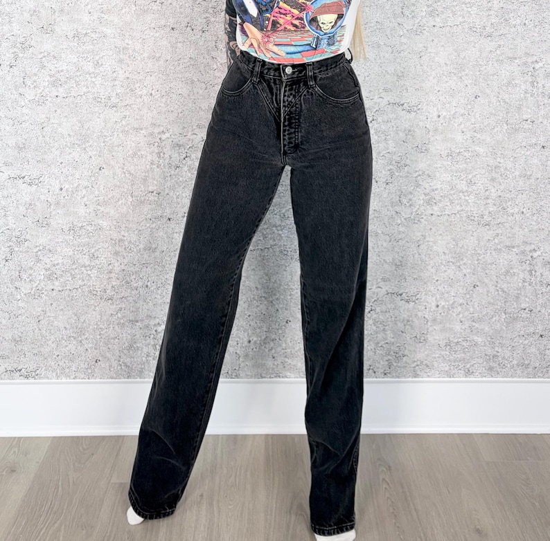 Pu&ograve; includere: Jeans neri a vita alta con chiusura a bottone e cerniera. I jeans hanno un design a gamba dritta e un classico stile a cinque tasche. Il denim &egrave; di un lavaggio scuro, con un leggero effetto sbiadito.