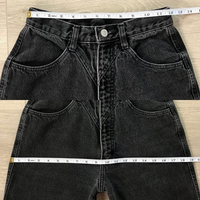 Pu&ograve; includere: Primo piano di jeans neri in denim con vita alta e design unico delle tasche. I jeans hanno una chiusura con bottoni e un classico stile a cinque tasche. Un metro a nastro &egrave; appoggiato sulla vita.
