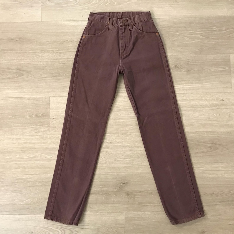 Op de afbeelding: Een paar mauve denim jeans. De jeans hebben een klassiek ontwerp met vijf zakken, een knoop- en ritssluiting en een hoge taille. De broek is gemaakt van stevig denim materiaal en lijkt vintage.