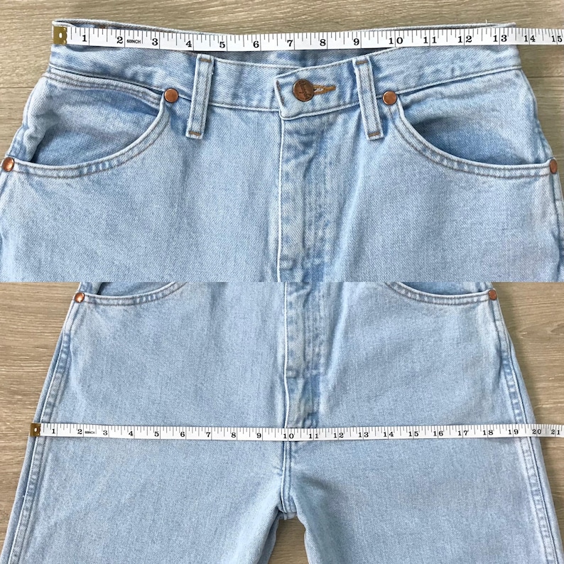 May include: Light blue denim jeans with a classic five-pocket design. The jeans are measured with a measuring tape, showing the waist and inseam. The jeans have copper-coloured rivets and a button closure.