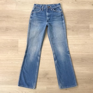 Op de afbeelding: Lichtblauwe spijkerbroek met een klassiek ontwerp met vijf zakken en een lichte flare aan de zoom. De jeans heeft een vervaagde wassing en een knoop- en ritssluiting. De jeans ligt plat op een licht houten oppervlak.