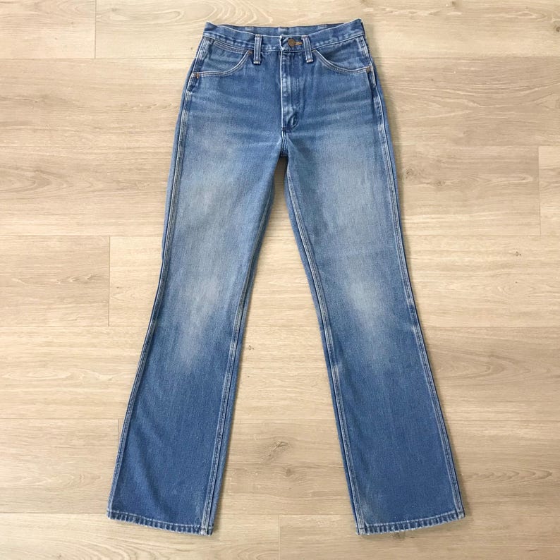 Op de afbeelding: Lichtblauwe spijkerbroek met een klassiek ontwerp met vijf zakken en een lichte flare aan de zoom. De jeans heeft een vervaagde wassing en een knoop- en ritssluiting. De jeans ligt plat op een licht houten oppervlak.