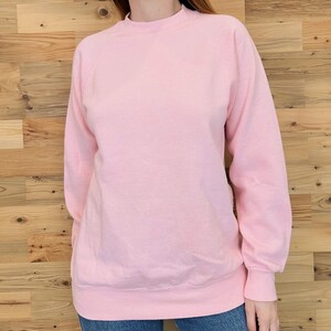 May include: A pink long-sleeved sweatshirt with a crew neck.