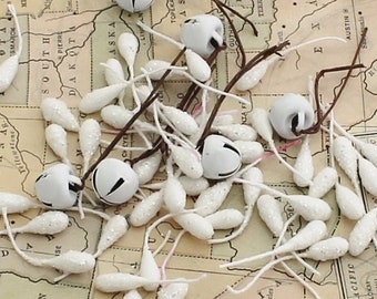 Könnte beinhalten: Eine Vintage-Karte der Vereinigten Staaten mit weißen, glockenförmigen Ornamenten, die darauf verstreut sind. Die Ornamente sind an dünnen weißen Schnüren befestigt.
