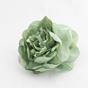 May include: A single, light green artificial flower with multiple layers of petals. The flower has a realistic appearance, with subtle variations in color and texture. The petals have a slight sheen, and the overall effect is delicate and elegant.