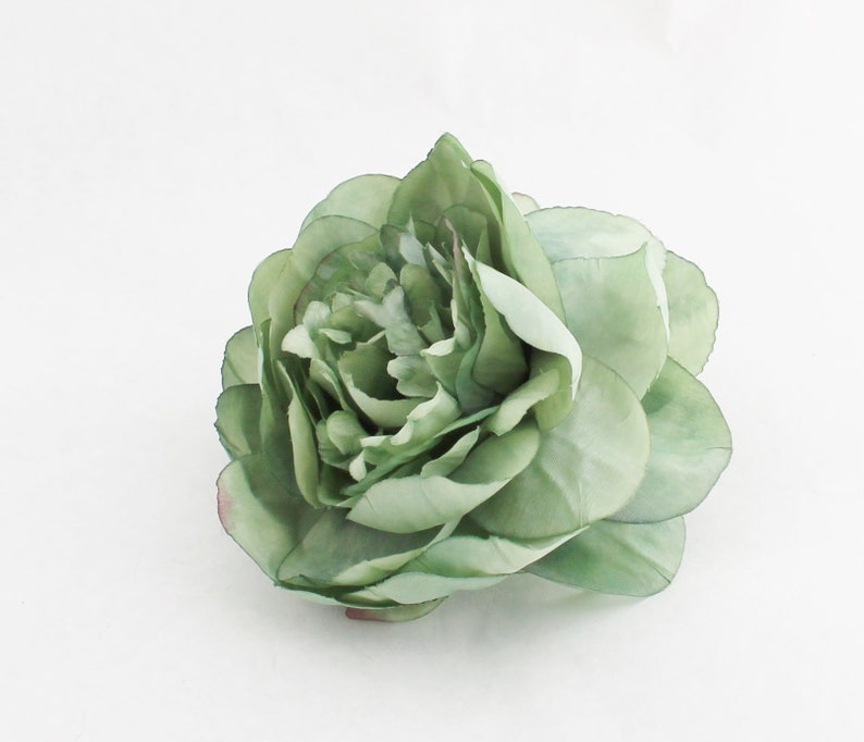 May include: A single, light green artificial flower with multiple layers of petals. The flower has a realistic appearance, with subtle variations in color and texture. The petals have a slight sheen, and the overall effect is delicate and elegant.