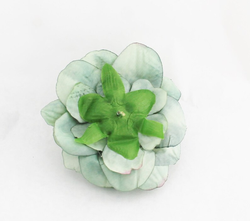 May include: A light green artificial succulent flower with layered petals and a bright green center. The flower has a small, sparkling embellishment in the center. The petals have a subtle pink hue at the edges.