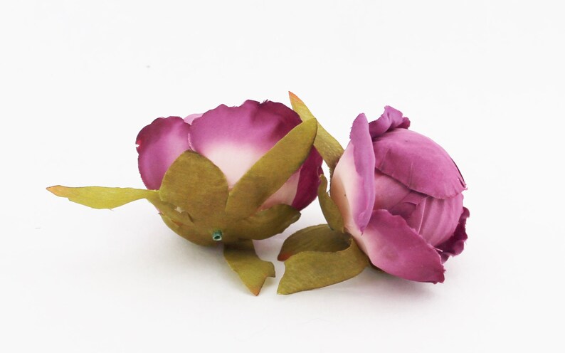May include: Two artificial peony flower buds. The petals are a gradient of deep magenta to light pink. The buds have green sepals and stems, set against a white background. These faux flowers are suitable for crafts and decor.