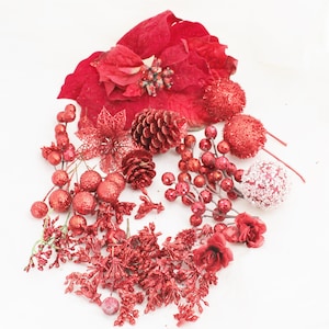 May include: Assortment of red Christmas decorations including poinsettia, berries, pine cones, and sparkly ornaments.