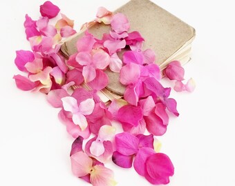 May include: A stack of brown paper notebooks with pink flower petals scattered around them.