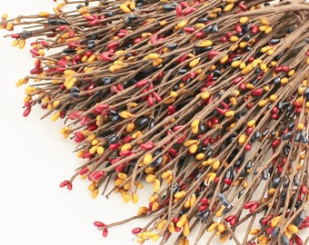 May include: A bunch of brown twigs with small red, yellow, and blue berries. The berries are clustered together on the twigs, creating a colorful and festive look.