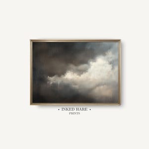 Op de afbeelding: Een rechthoekige ingelijste kunstdruk met een olieverfschilderij van een dramatische, stormachtige lucht met donkere houtskoolkleurige wolken die contrasteren met heldere witte, verlichte wolkenformaties. De tekst INKED HARE PRINTS staat gecentreerd eronder.