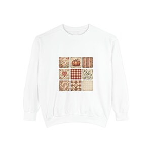 May include: A white long-sleeve sweatshirt featuring a central graphic composed of nine square tiles. The tiles display various patterns including a pumpkin, a red heart, red and white gingham, paisley, stripes, and botanical leaf motifs.