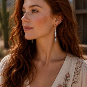 May include: A dangle earring featuring a vertical arrangement of small, flat, circular beads in alternating shades of light blue and soft pink, separated by metallic silver spacer beads, suspended from a simple silver-toned hook wire.