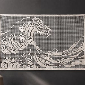 May include: A rectangular wall hanging featuring a white crocheted grid pattern that depicts a large crashing wave and a distant mountain. The design is created using a series of small, interconnected squares, forming a detailed graphic image.