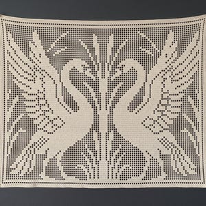 Peut inclure: Une tenture murale carrée en crochet blanc cassé présentant un motif filet symétrique de deux cygnes se faisant face, les ailes déployées vers le haut. Le travail d'aiguille complexe crée un design en grille avec des espaces vides.