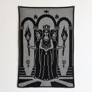 Könnte beinhalten: Ein rechteckiger Wandbehang aus schwarz-weißem Häkelgarn mit einer zentralen gekrönten Figur, flankiert von zwei Fackelträgern. Das Design ist in einen architektonischen Bogenrahmen eingebettet, mit Schlüsseln an der Basis der Säulen.